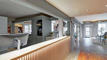 Een moderne receptiebalie met een houten toonbank, een glazen scheidingswand en uitzicht op de lobby.