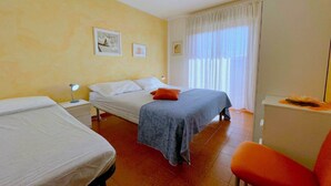 A hotel room with two beds, a desk, a chair, and a window with curtains. - Apartment near the centre of Caorle (Caorle (VE))