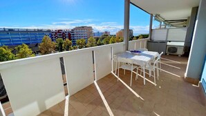 A balcony with a table and chairs, a view of buildings, and a clear sky. - Apartment near the centre of Caorle (Caorle (VE))