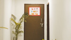 A hallway with a door, potted plants, and a sign with country names. - Roomshala 124 Royal inn Rohini (New Delhi)
