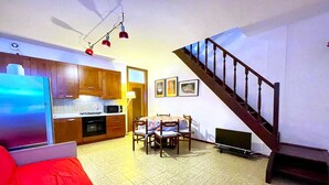 Um espaço de estar compacto com cozinha, área de refeições e escada.