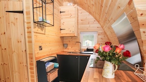 A compact kitchen with wooden walls, a built-in sink, and a stainless steel refrigerator. - The Pod (Shrewsbury)