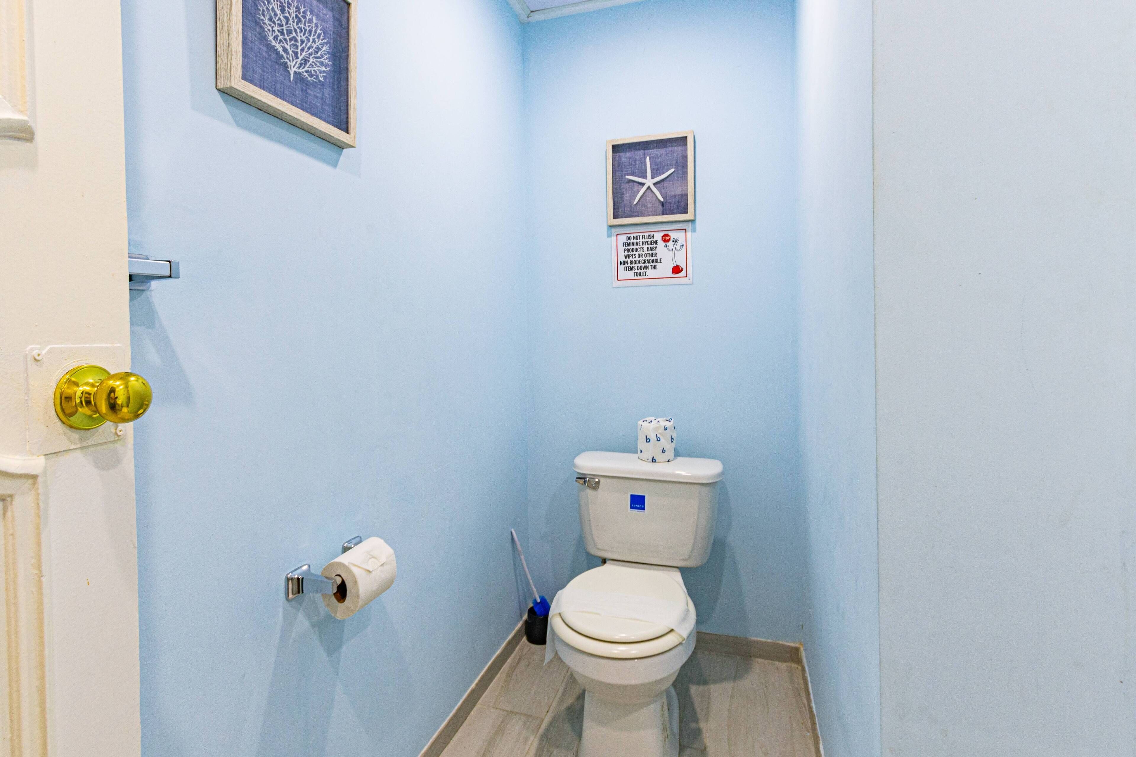 Une petite salle de bain avec des toilettes, un rouleau de papier toilette et un distributeur de gel hydroalcoolique.