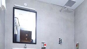 A modern bathroom with a white sink, a large mirror, and a shower area. - Roomshala 041 Hotel Sky Residency (New Delhi)