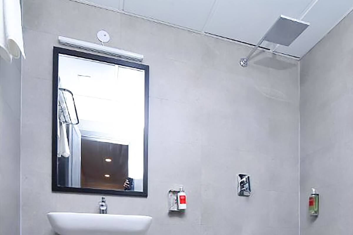 A modern bathroom with a white sink, a large mirror, and a shower area.