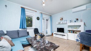 Un salon avec un canapé, une table basse, un téléviseur et un meuble blanc.