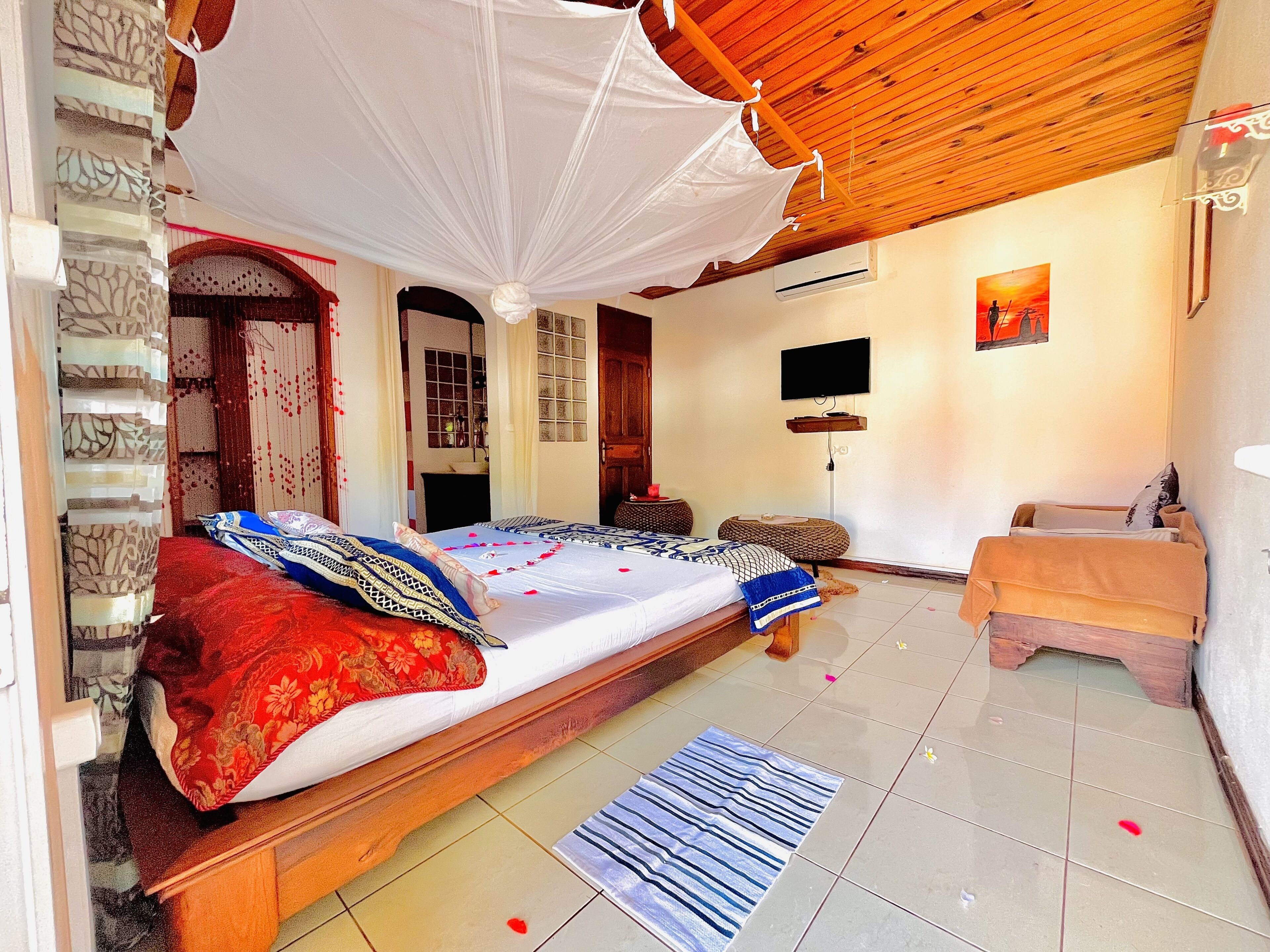 A room with a bed, a TV, a small table, and a bench.