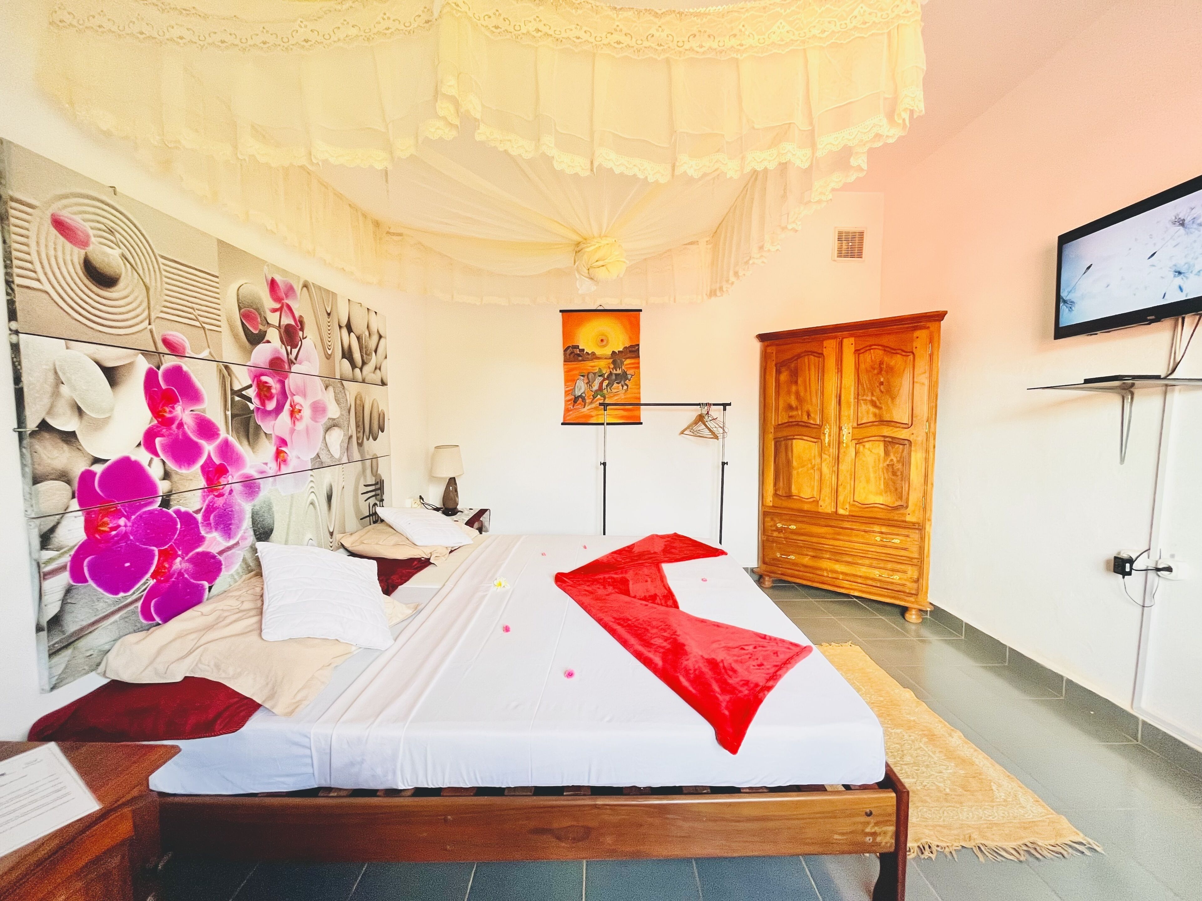 Habitación de hotel con cama, armario de madera, televisor y pared decorada.