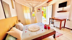 A bedroom with a bed, a desk, and a television. - Régina Lodge (Antsiranana)