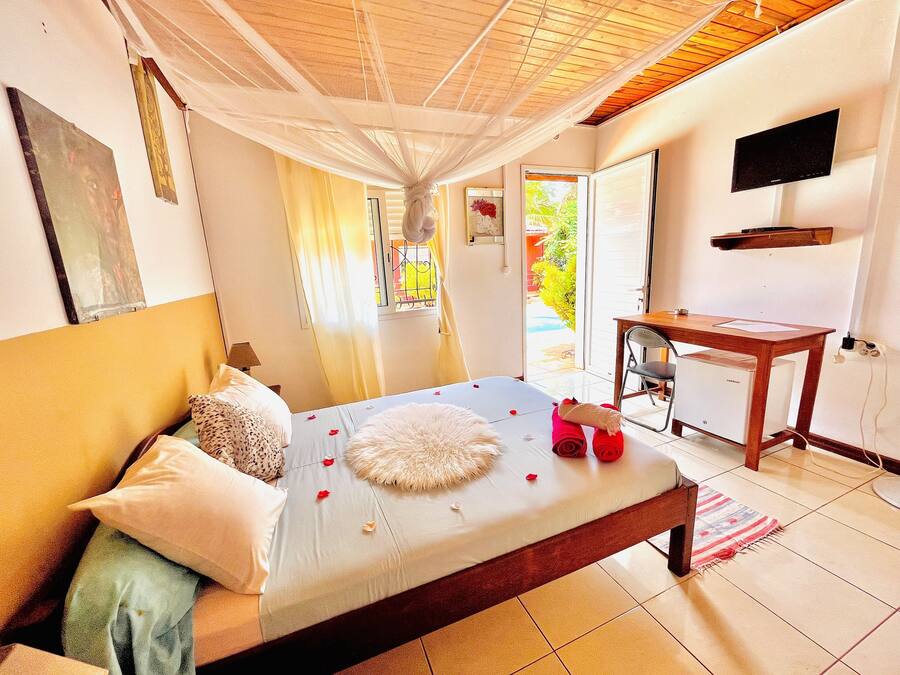 A bedroom with a bed, a desk, and a television.