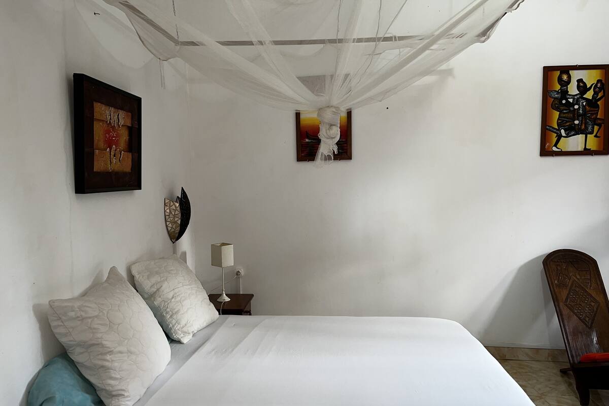 A bedroom with a large bed, a nightstand, a lamp, and artwork on the walls.