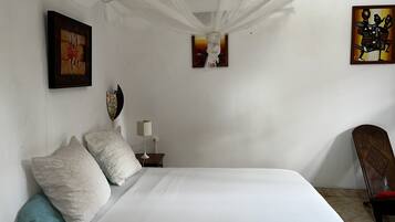 A bedroom with a large bed, a nightstand, a lamp, and artwork on the walls.