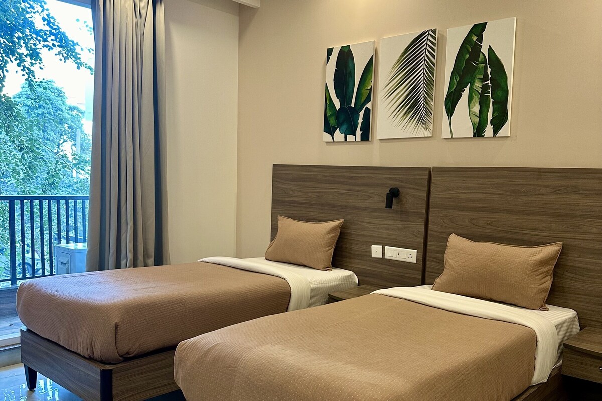 A hotel room with two beds, a balcony, and artwork on the wall.