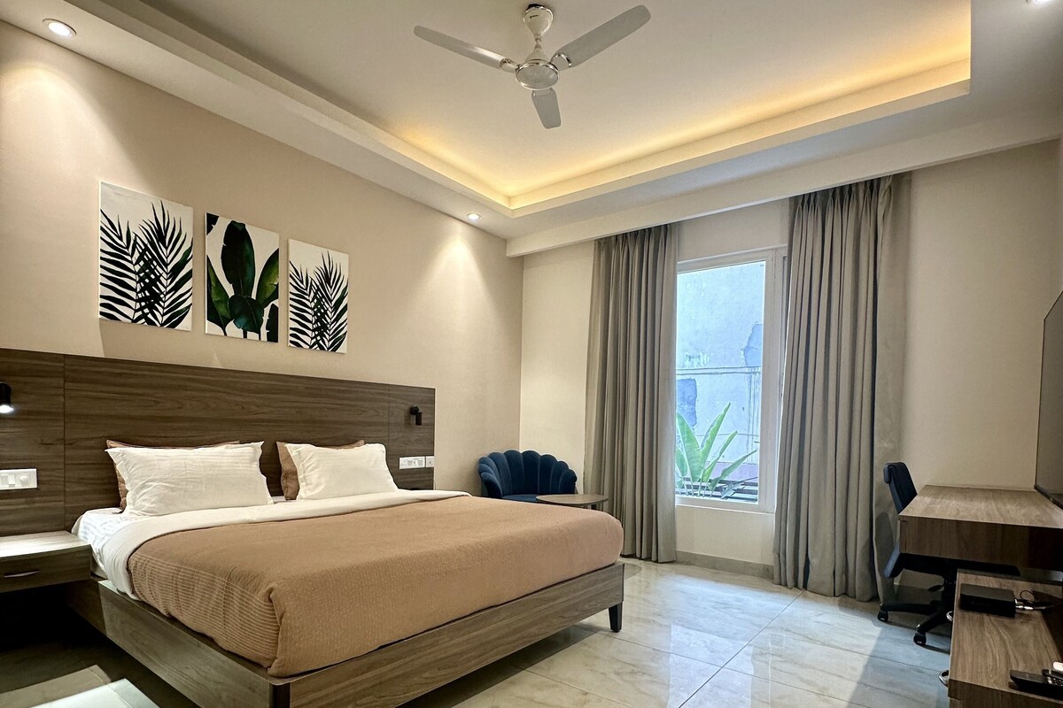 A modern hotel room with a large bed, a desk, and a ceiling fan.