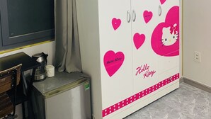 A room with a white wardrobe decorated with Hello Kitty motifs, a blackboard, and a small kitchenette area. - Homestay 26 Nguyen Van Lac (Ho Chi Minh City)