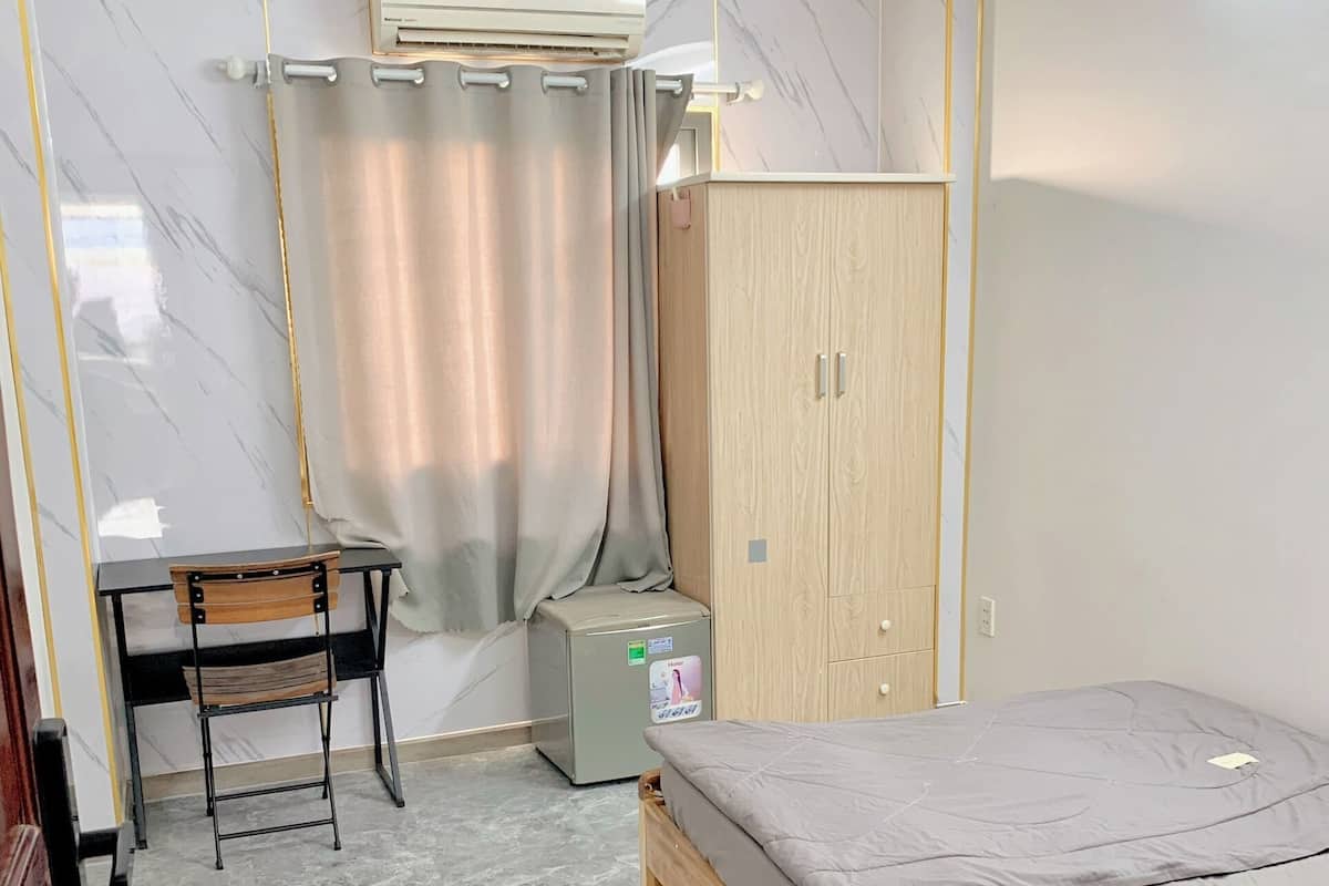 Een slaapkamer met een bed, een bureau, een stoel, een kledingkast en een airconditioner.