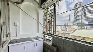 A narrow balcony with a sink and cabinets, overlooking a cityscape with modern buildings. - Homestay 26 Nguyen Van Lac (Ho Chi Minh City)