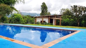 A swimming pool with a wooden deck and a house in the background.
