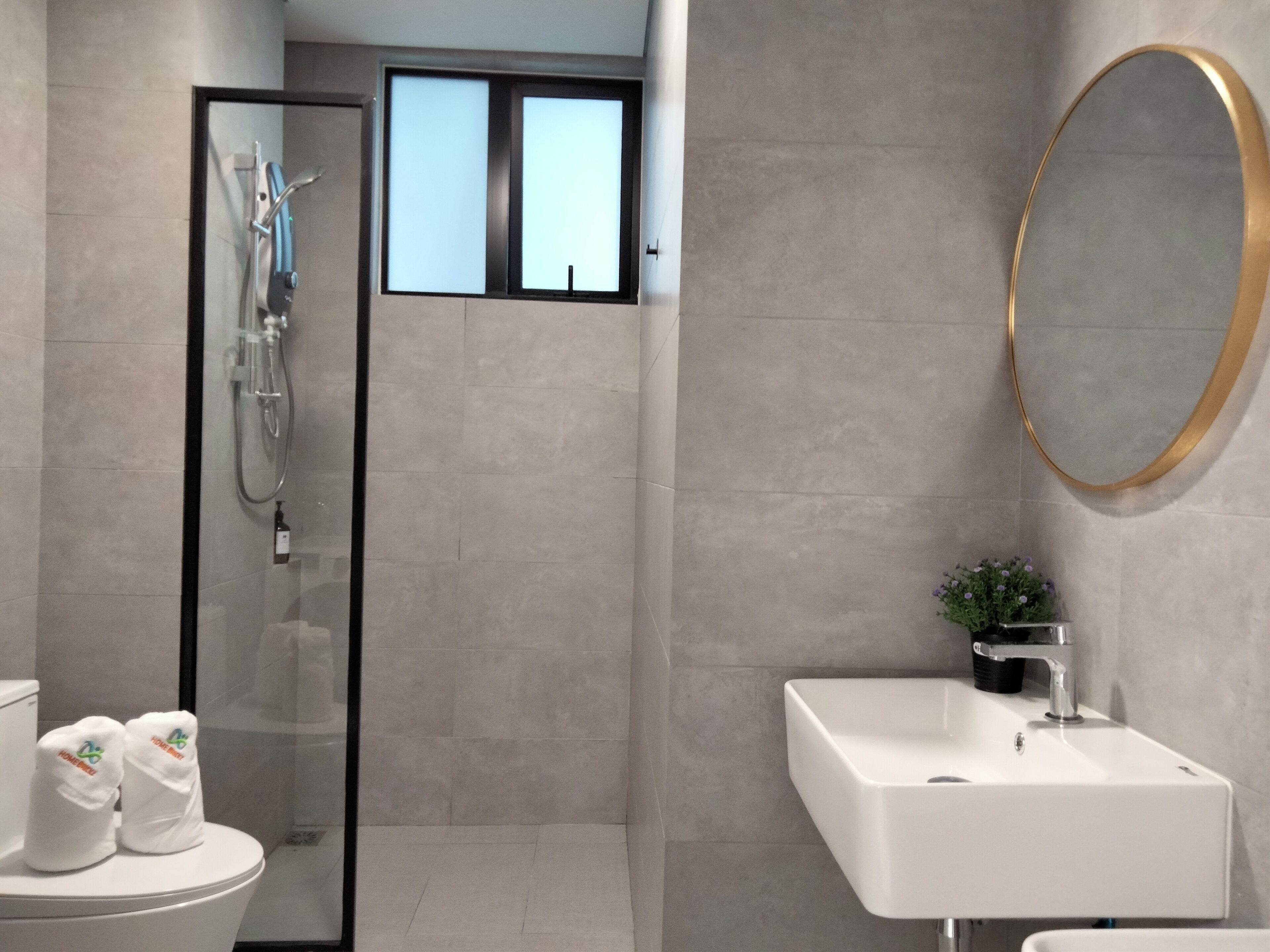 A modern bathroom with a glass-enclosed shower, a white sink, and a large mirror.