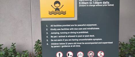 A sign for a private kid's pool with rules and regulations, including operating hours and a list of prohibitions.
