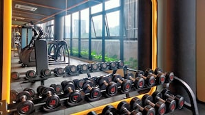 A gym with a mirrored wall reflecting the interior, including a rack of dumbbells and exercise equipment. - Cubic Botanical Suites HomeBrickz (Kuala Lumpur)