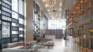 A spacious lobby with large windows, a reception desk, and modern furniture. - Cubic Botanical Suites HomeBrickz (Kuala Lumpur)