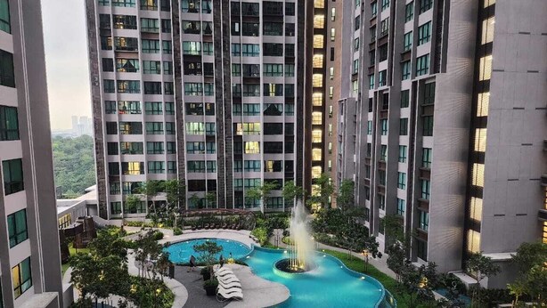 A high-rise residential building with a landscaped swimming pool area, including a fountain and lounge chairs. - Cubic Botanical Suites HomeBrickz (Kuala Lumpur)