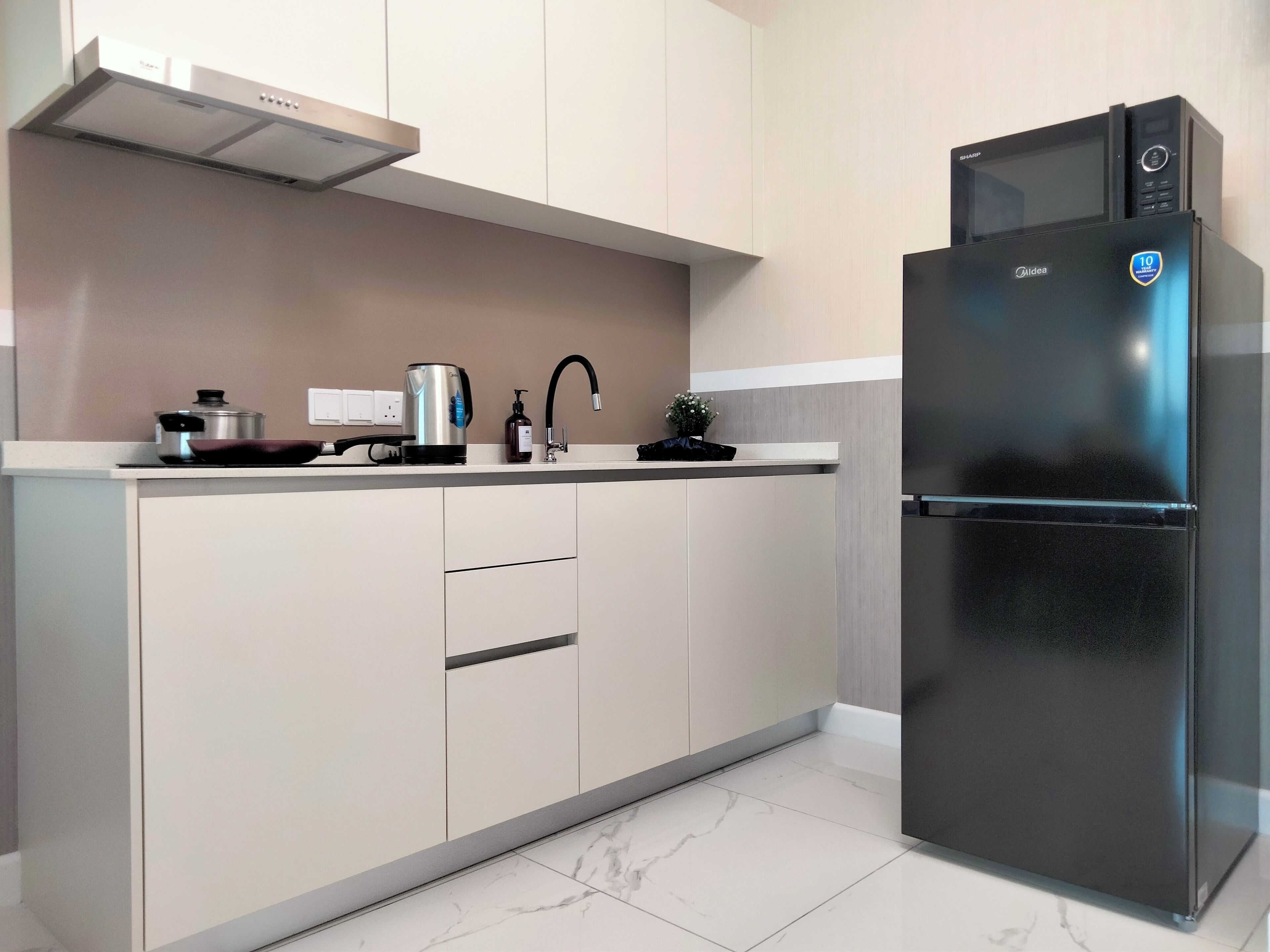 A modern kitchen with a stainless steel refrigerator, a kettle, a coffee maker, and a sink.