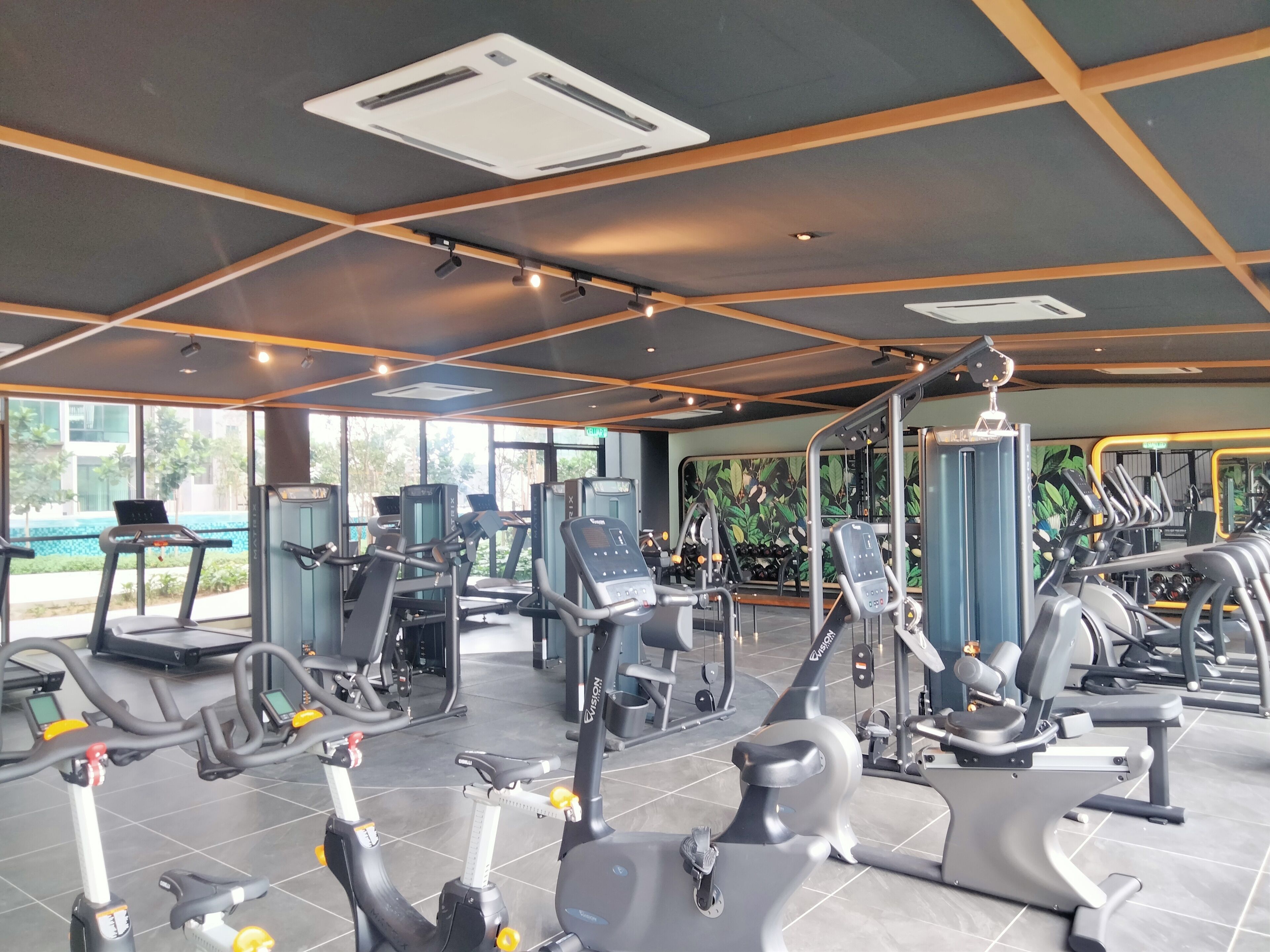 Uma academia moderna com diversos equipamentos de ginástica, grandes janelas e um interior limpo e bem iluminado.