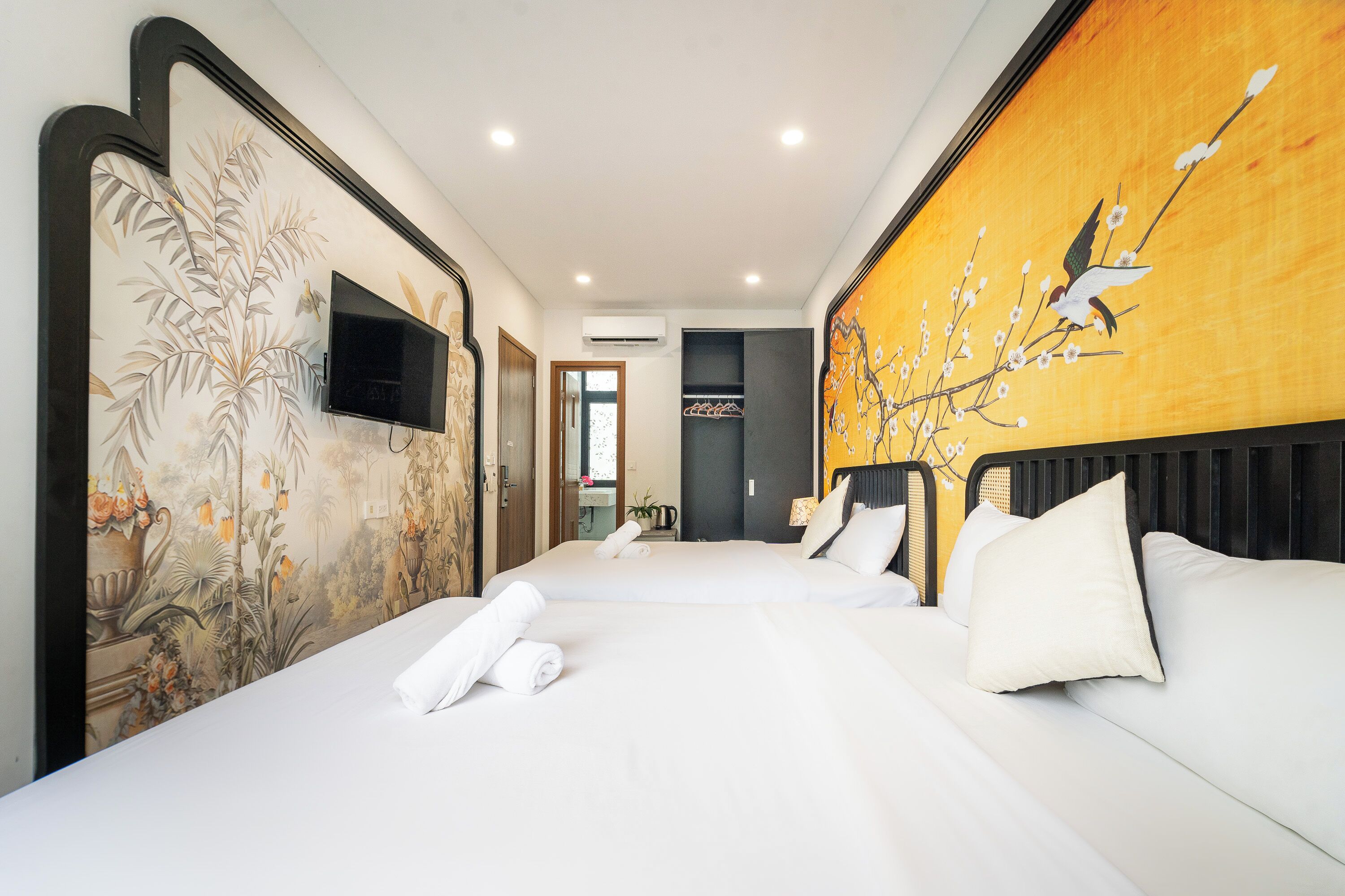 A hotel room with two beds, a television, and a mural on the wall.