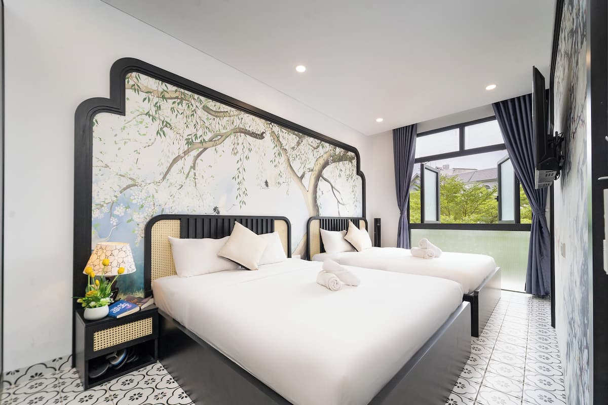 A hotel room with two beds, a large window, and a decorative wall mural.