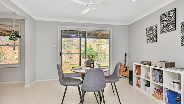Un coin repas avec une table dressée pour deux personnes, une guitare et une bibliothèque contenant des livres et des objets décoratifs.