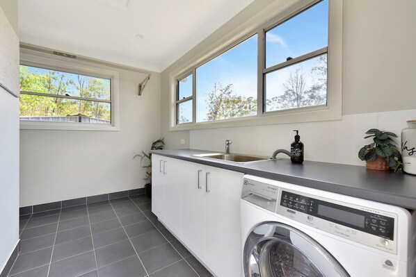 A compact kitchen with a built-in dishwasher, a sink, and a window overlooking a garden.