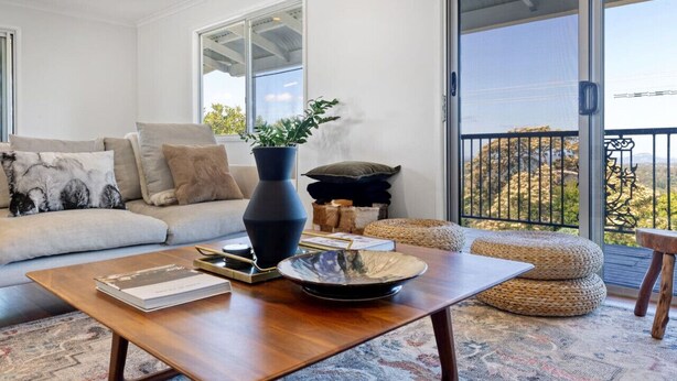 A modern living room with a sofa, coffee table, and a view of the outdoors through a sliding glass door.