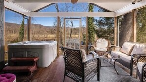 A covered outdoor area with a hot tub, wicker furniture, and a ceiling fan. - Beautiful Riverfront Retreats | Sleeps 24 w/ Hot Tubs, Firepits & Scenic Views (Shenandoah)