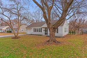 A residential house with a front yard, a driveway, and a tree in the foreground.