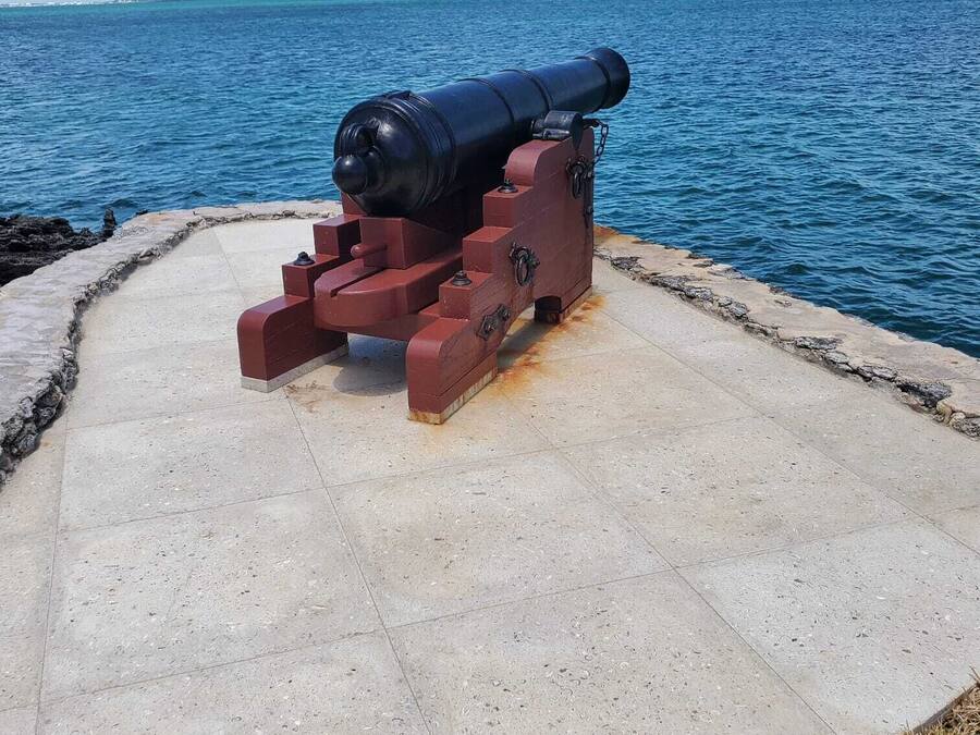 Un cañón sobre una plataforma de hormigón junto al agua.