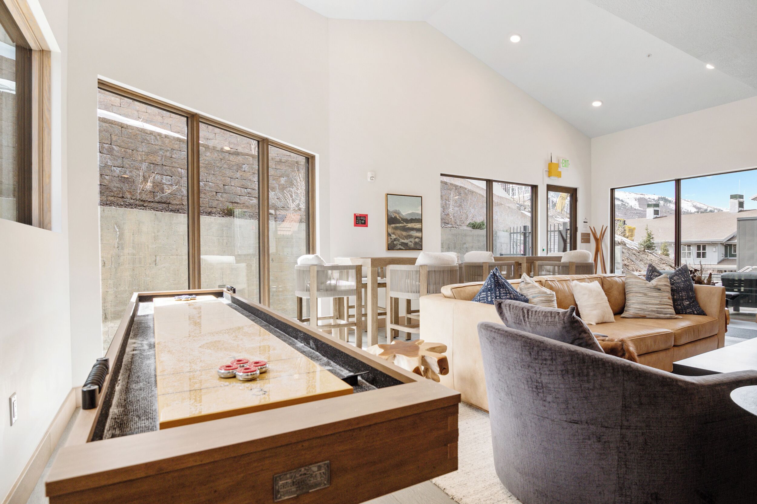 A spacious living area with a pool table, comfortable seating, and large windows offering views of the outdoors.