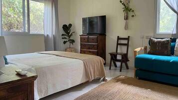 Une chambre avec deux lits, une télévision, un bureau, une chaise et un canapé.