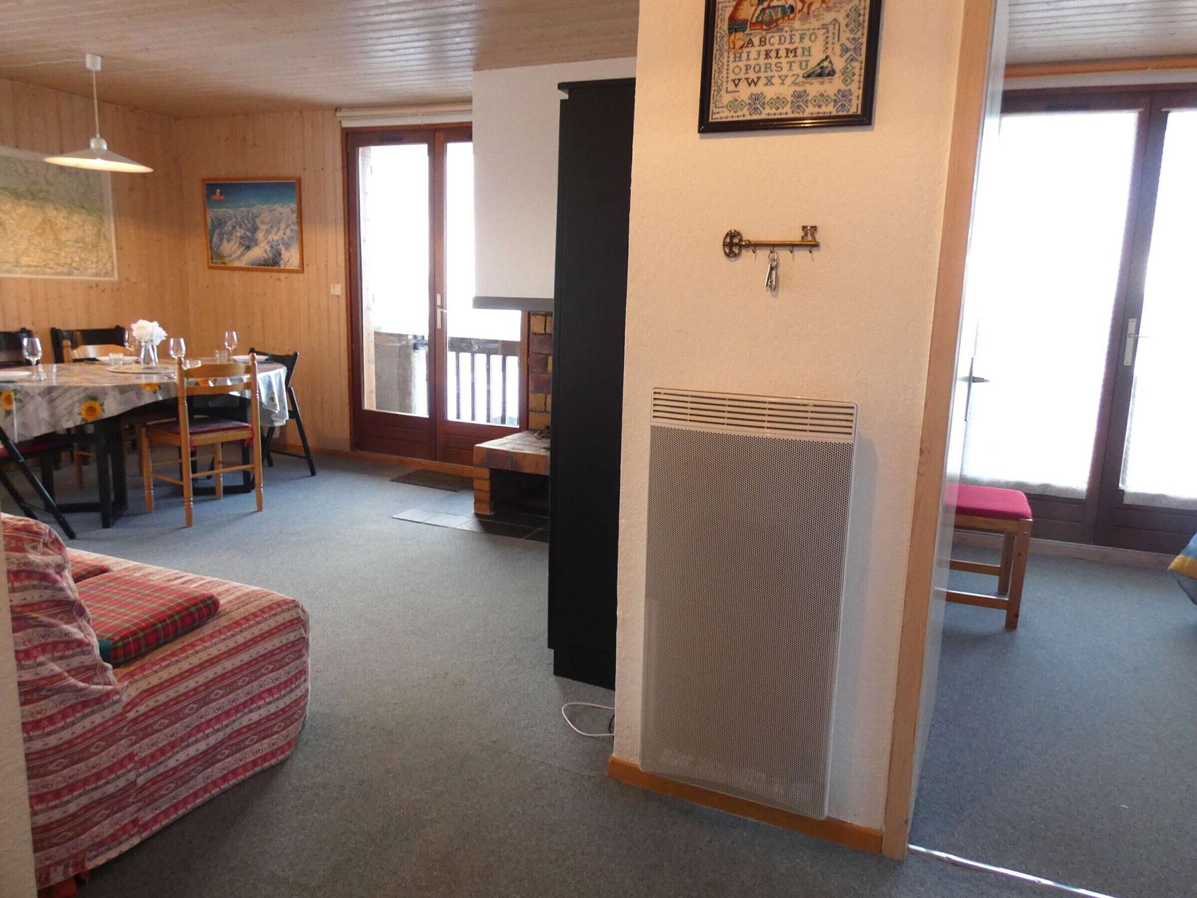 A cozy living room with a dining area, a sofa, a table with chairs, a radiator, and a door leading outside.