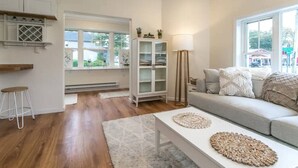 Un salon comprenant un canapé, une table basse, un meuble et un lampadaire.