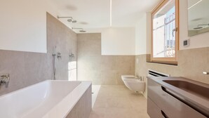 Un baño moderno con una bañera grande, una zona de ducha separada, un inodoro y un lavamanos con lavabo.