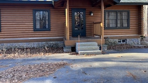 A log cabin with a stone foundation, a front porch, and a metal roof. - Cozy cabin near Conway Lake and North Conway (Center Conway)
