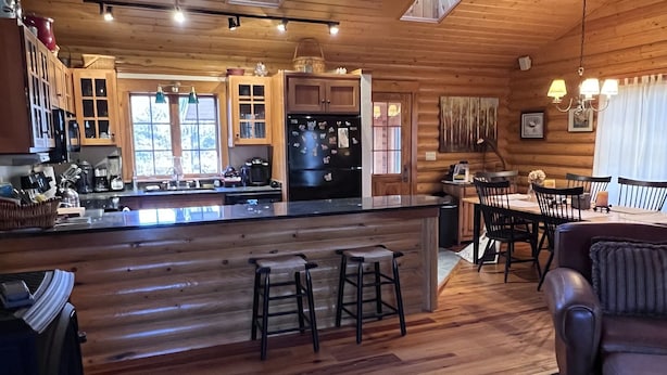 A wooden cabin interior with a kitchen, dining area, and a bar. - Cozy cabin near Conway Lake and North Conway (Center Conway)