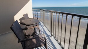 A balcony with wicker furniture and a view of the ocean.