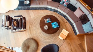 Ein modernes Wohnzimmer mit einer gebogenen Eckcouch, einem runden Couchtisch und einem großen Teppich.