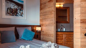 Ein Hotelzimmer mit Holzwand, einem Bett mit Kissen, einem Nachttisch mit Lampe und einem gerahmten Bild an der Wand.