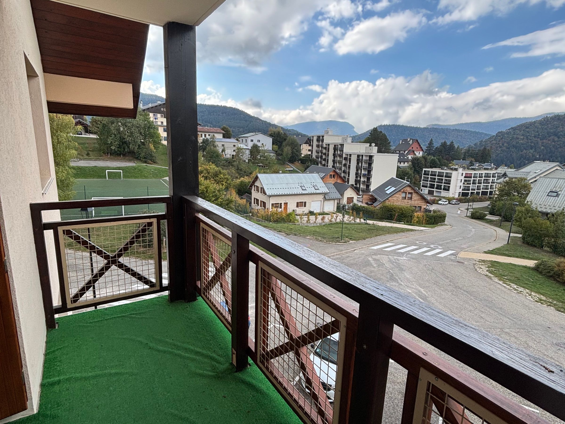 Un balcon donnant sur un quartier résidentiel, avec vue sur des maisons et un terrain de sport.