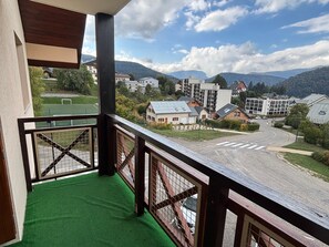 Un balcó amb vista a una zona residencial, incloent cases i un camp esportiu.