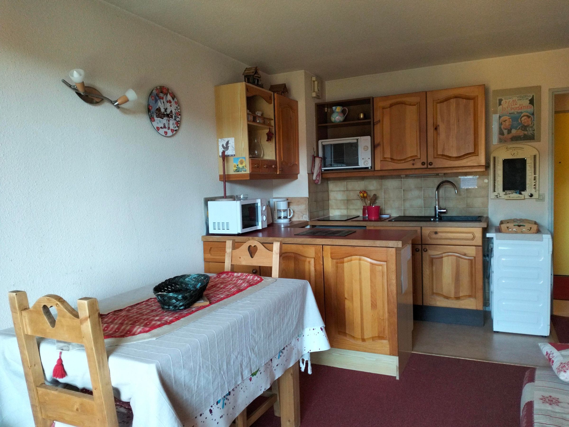 A compact kitchen with wooden cabinets, a microwave, a sink, and a small refrigerator.